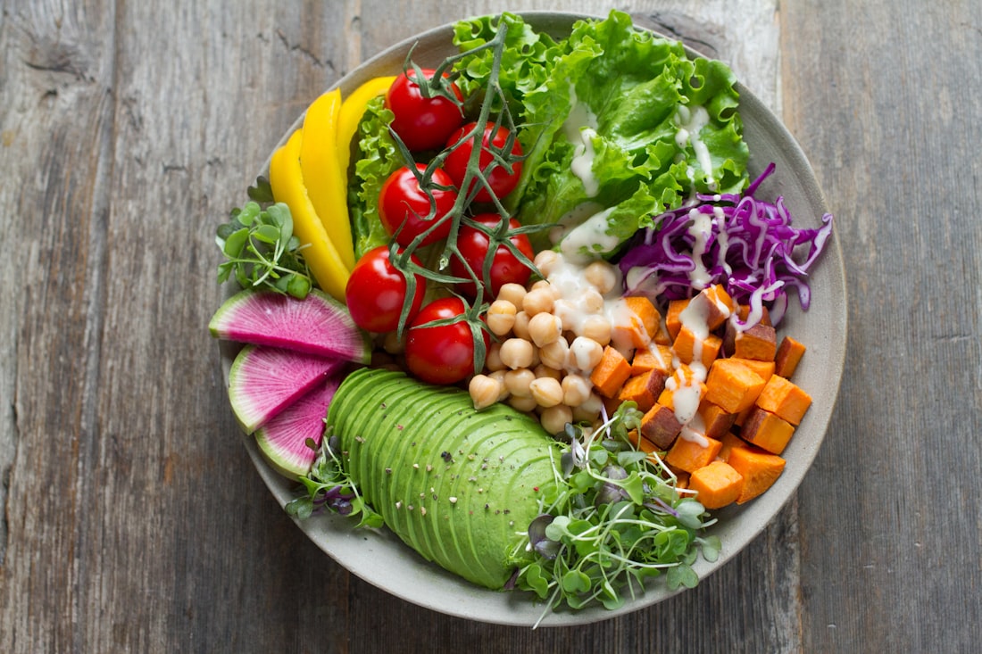 A generous bowl of greens, tomatoes, avocado, chickpeas, and roasted sweet potato